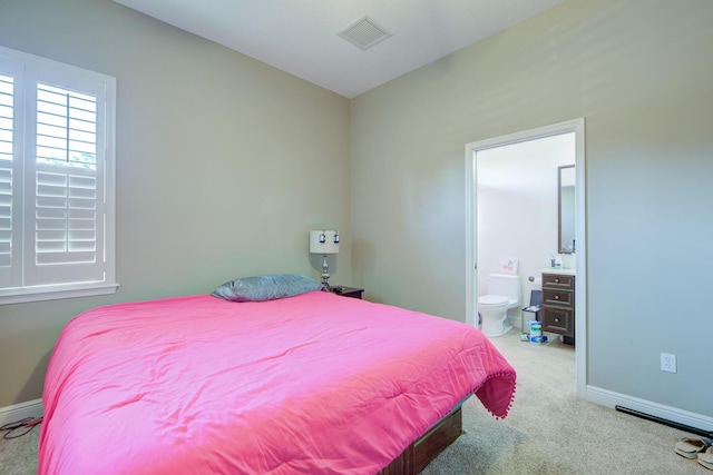 bedroom featuring ensuite bath and light carpet