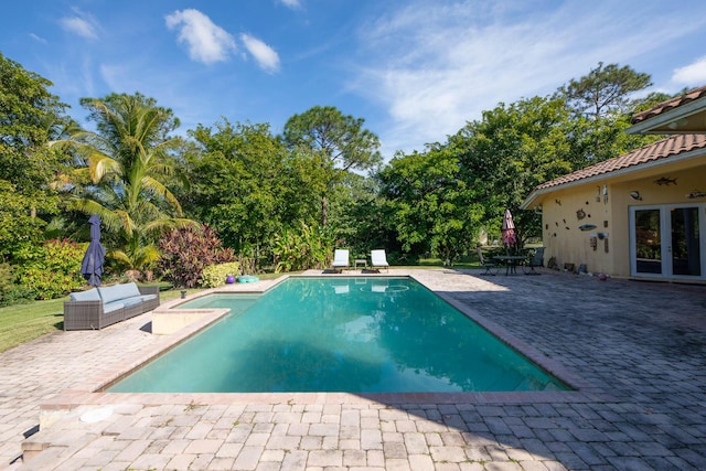 view of swimming pool with french doors, outdoor lounge area, and a patio