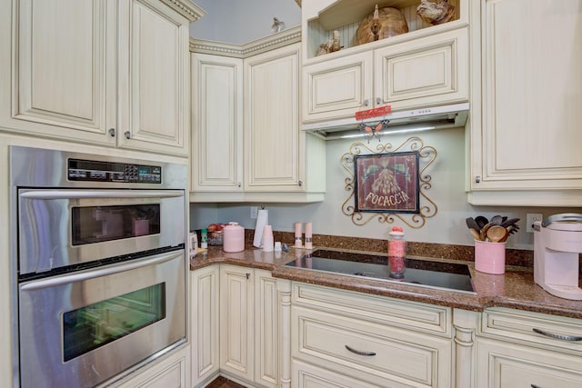 kitchen with cream cabinets, sink, stainless steel double oven, and dark stone counters