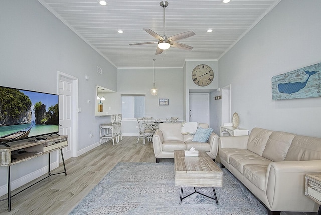 living room featuring ceiling fan, ornamental molding, light hardwood / wood-style floors, and a towering ceiling