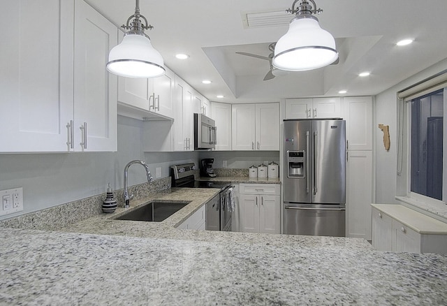 kitchen with white cabinetry, sink, a tray ceiling, stainless steel appliances, and light stone countertops