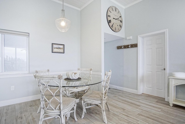 dining room with high vaulted ceiling, crown molding, and light hardwood / wood-style floors