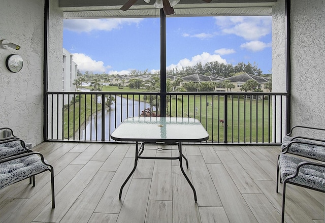 sunroom / solarium featuring ceiling fan and a water view