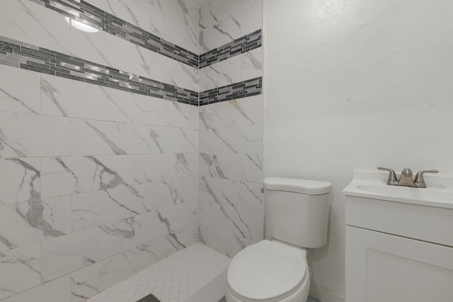 bathroom featuring tiled shower, vanity, and toilet