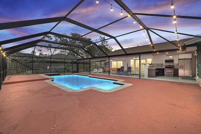 pool at dusk featuring area for grilling, glass enclosure, and a patio area