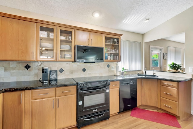 3215 NW 12th St, Delray Beach, FL 33445 - kitchen featuring black appliances, a sink, light wood finished floors, a textured ceiling, and a peninsula