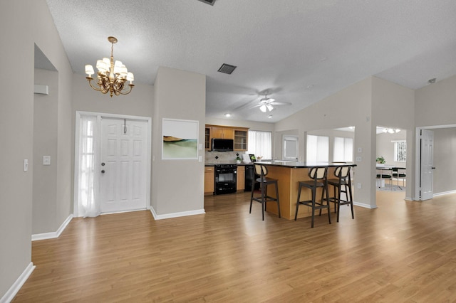 3215 NW 12th St, Delray Beach, FL 33445 - kitchen featuring a kitchen breakfast bar, black appliances, a chandelier, dark countertops, and light wood finished floors