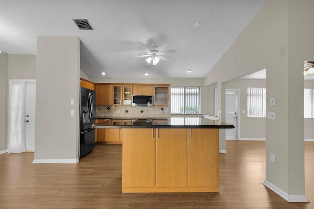 3215 NW 12th St, Delray Beach, FL 33445 - kitchen featuring black fridge, ceiling fan, stainless steel microwave, light wood finished floors, and a textured ceiling