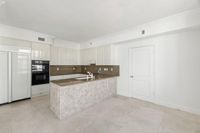 kitchen with paneled built in refrigerator, black double oven, white cabinets, sink, and kitchen peninsula