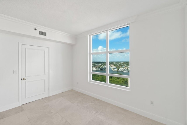 spare room with ornamental molding, a water view, and a textured ceiling