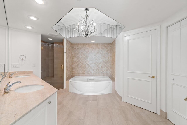 bathroom featuring vanity, a notable chandelier, and shower with separate bathtub