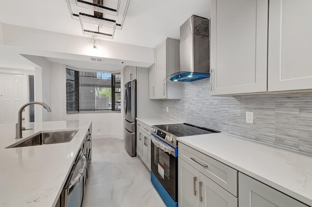 kitchen featuring backsplash, wall chimney range hood, marble finish floor, stainless steel appliances, and a sink