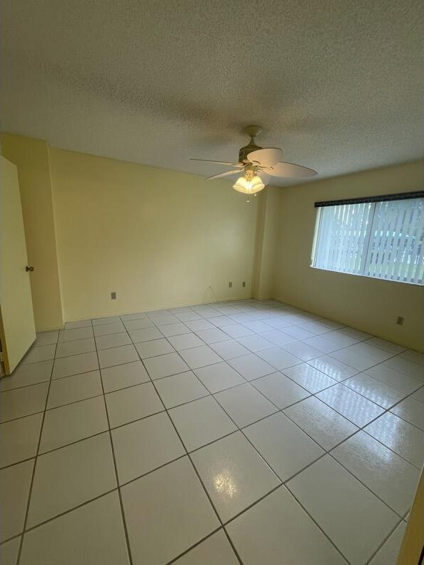 spare room with a textured ceiling, ceiling fan, and light tile patterned flooring