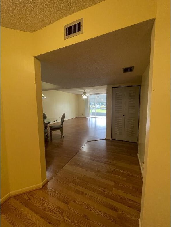 hall with hardwood / wood-style floors and a textured ceiling