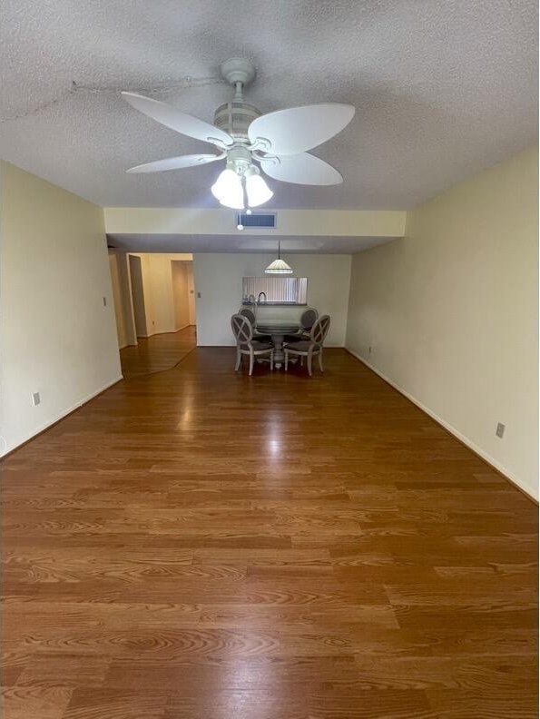 unfurnished dining area with ceiling fan, wood-type flooring, and a textured ceiling