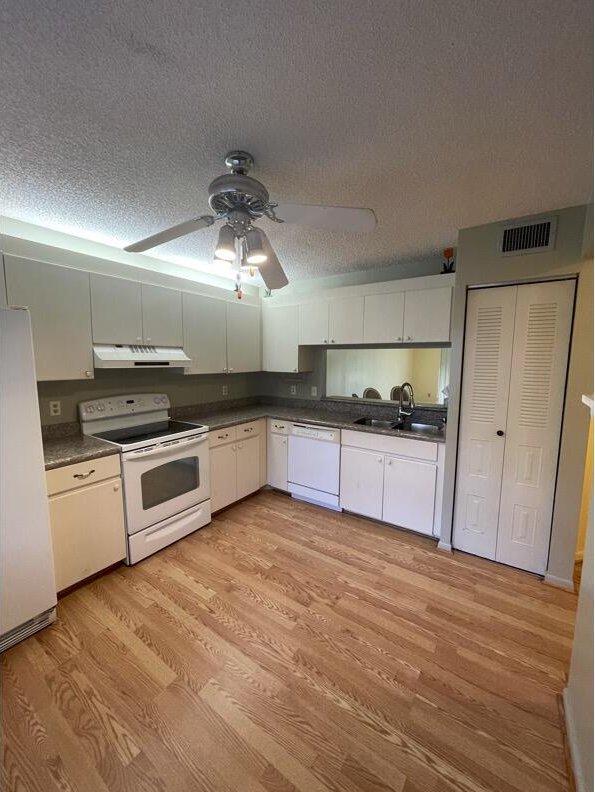 kitchen with white appliances, sink, light hardwood / wood-style flooring, and white cabinets