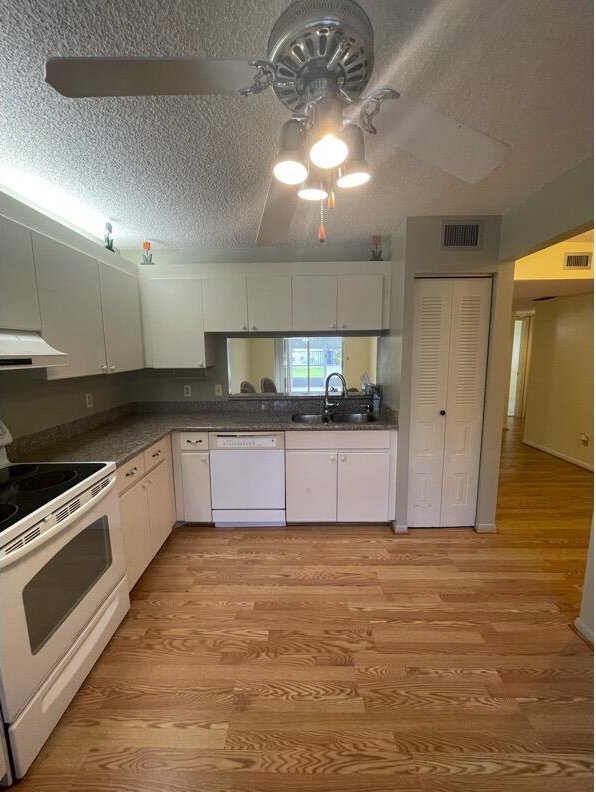 kitchen featuring white cabinetry, sink, white appliances, and light hardwood / wood-style floors