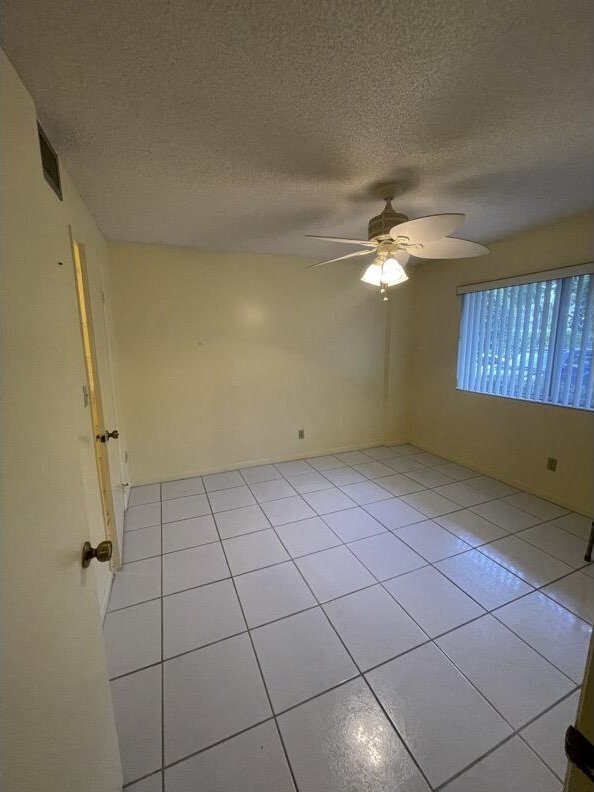 unfurnished room featuring light tile patterned flooring, ceiling fan, and a textured ceiling