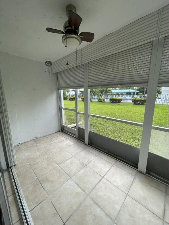 unfurnished sunroom with ceiling fan