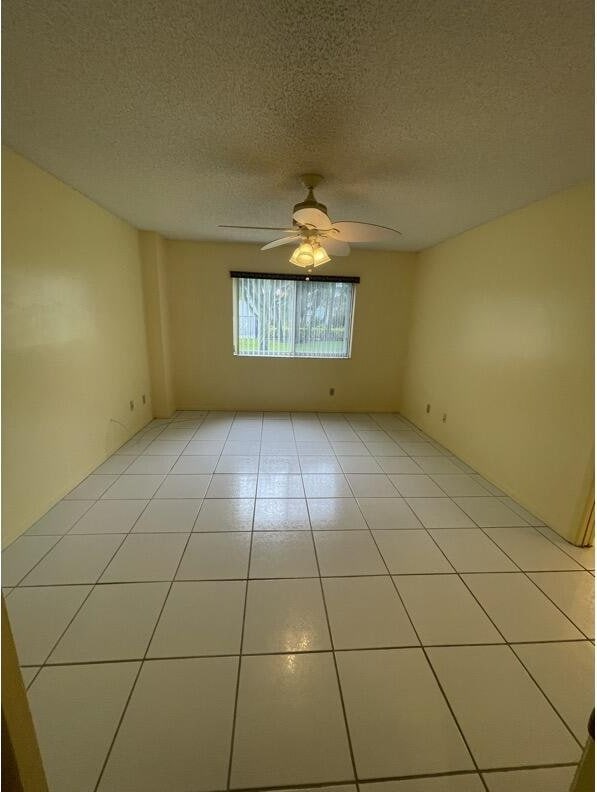 unfurnished room featuring light tile patterned floors, a textured ceiling, and ceiling fan