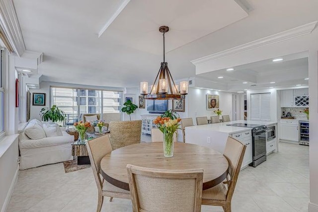 tiled dining space with a tray ceiling, ornamental molding, beverage cooler, and a chandelier