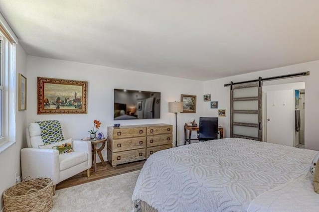 bedroom featuring multiple windows, light hardwood / wood-style floors, and a barn door