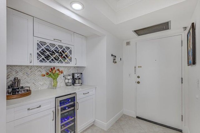 bar with wine cooler, light tile patterned floors, white cabinetry, and decorative backsplash