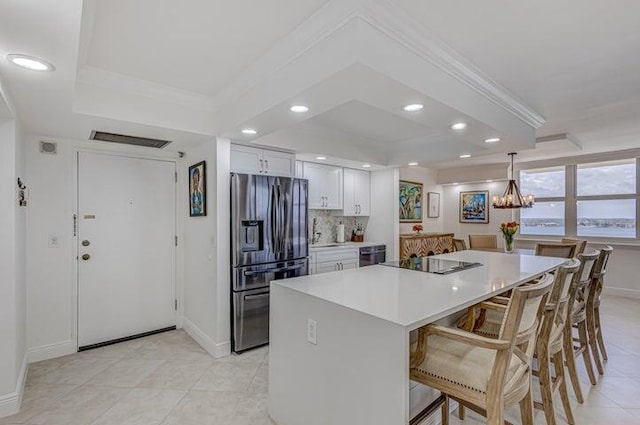 kitchen with pendant lighting, white cabinets, a kitchen bar, black electric cooktop, and stainless steel fridge with ice dispenser