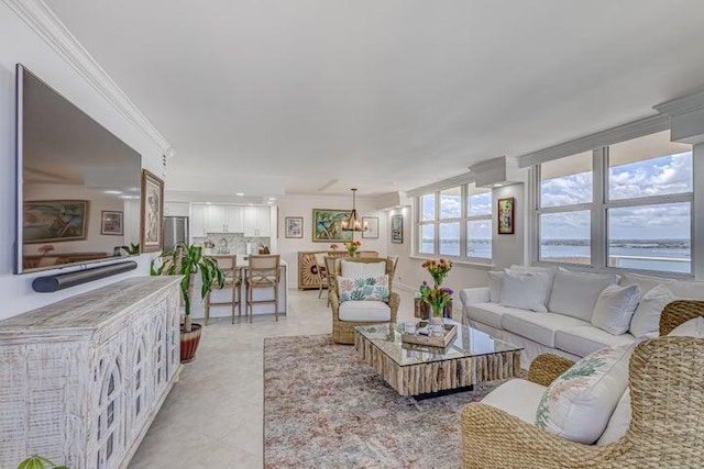 living room featuring light tile patterned floors, a notable chandelier, ornamental molding, and a water view