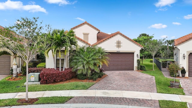 mediterranean / spanish home with a garage and a front lawn