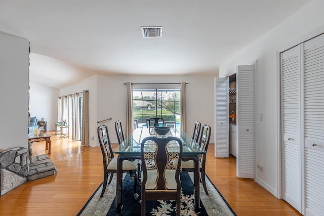 dining room featuring lofted ceiling, baseboards, visible vents, and light wood-style floors