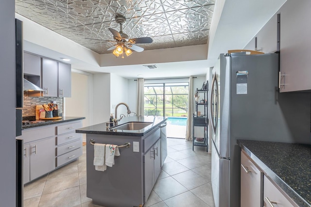 kitchen with a raised ceiling, visible vents, decorative backsplash, light tile patterned flooring, and a sink