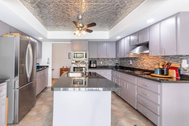 kitchen featuring a raised ceiling, an ornate ceiling, appliances with stainless steel finishes, wall chimney range hood, and backsplash