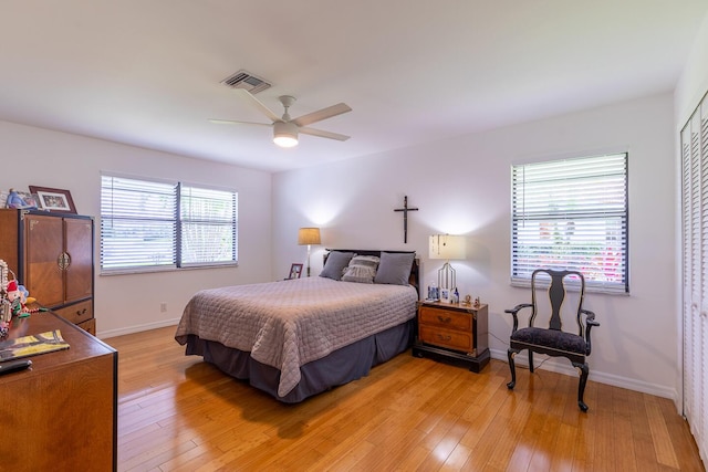 bedroom with ceiling fan, light wood-type flooring, visible vents, and baseboards