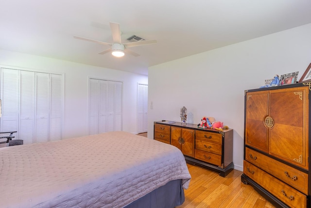 bedroom featuring multiple closets, light wood-type flooring, visible vents, and ceiling fan