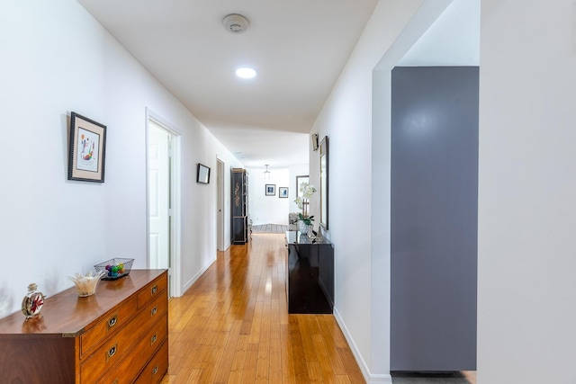 corridor featuring light wood-style flooring and baseboards