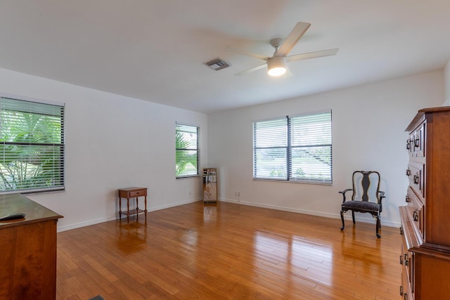 sitting room featuring light wood-style floors, baseboards, visible vents, and a ceiling fan