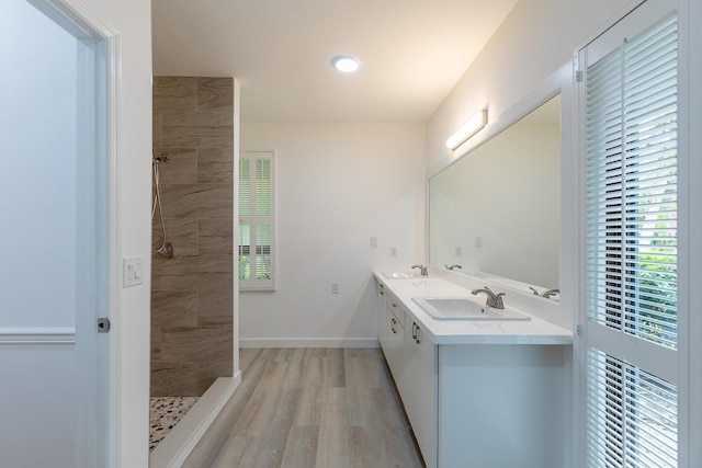 bathroom featuring wood finished floors, tiled shower, plenty of natural light, and a sink