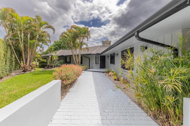 ranch-style home with a tile roof, a chimney, and a front lawn