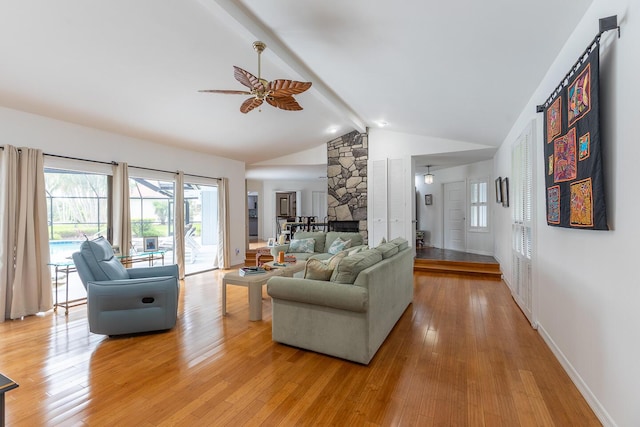 living area featuring light wood-type flooring, a wealth of natural light, a fireplace, and beam ceiling