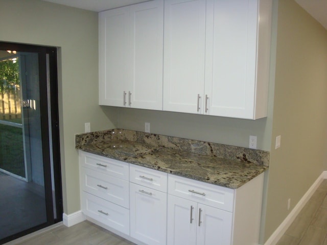 kitchen with dark stone countertops, light wood-type flooring, and white cabinets