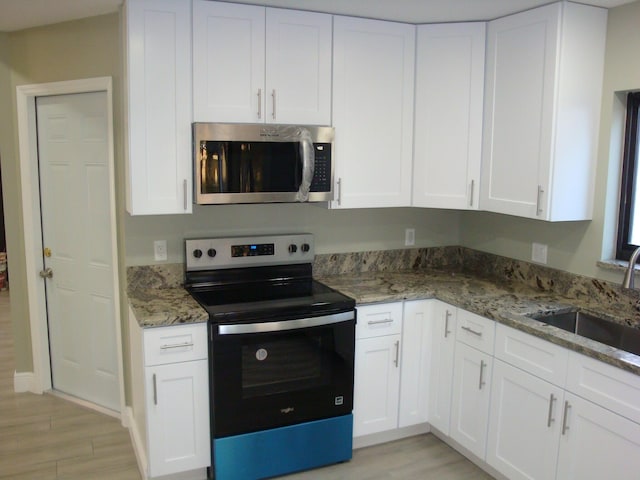 kitchen with sink, stainless steel appliances, white cabinets, and stone countertops