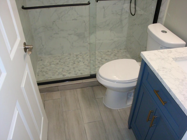 bathroom with a shower with door, vanity, and toilet