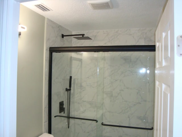 bathroom with a shower with door and a textured ceiling