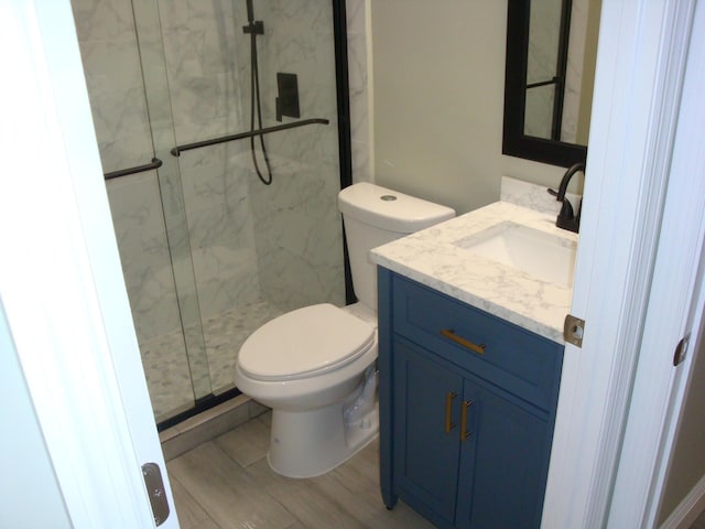 bathroom featuring vanity, hardwood / wood-style flooring, a shower with door, and toilet