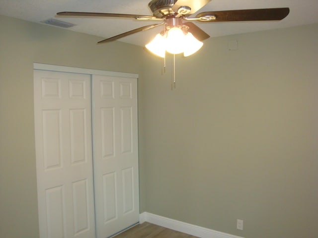 unfurnished bedroom featuring hardwood / wood-style flooring, a closet, and ceiling fan