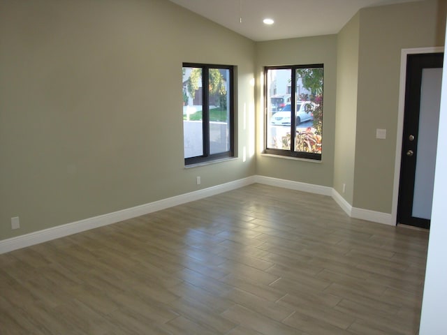 spare room featuring vaulted ceiling and light hardwood / wood-style flooring