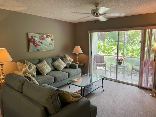 living room featuring light colored carpet, a textured ceiling, and ceiling fan