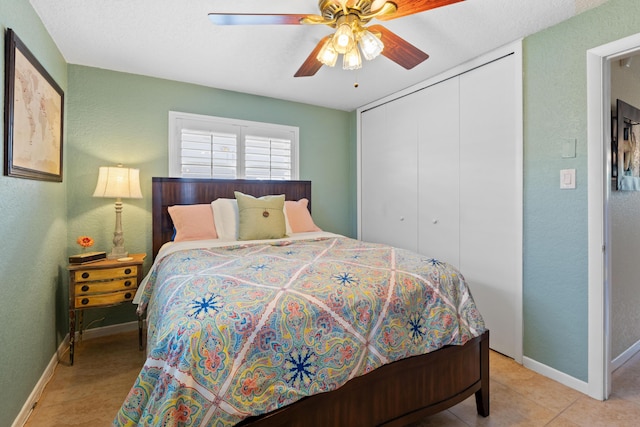 bedroom with ceiling fan, a closet, light tile patterned flooring, and baseboards