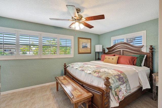 bedroom featuring a ceiling fan, a textured ceiling, baseboards, and tile patterned floors